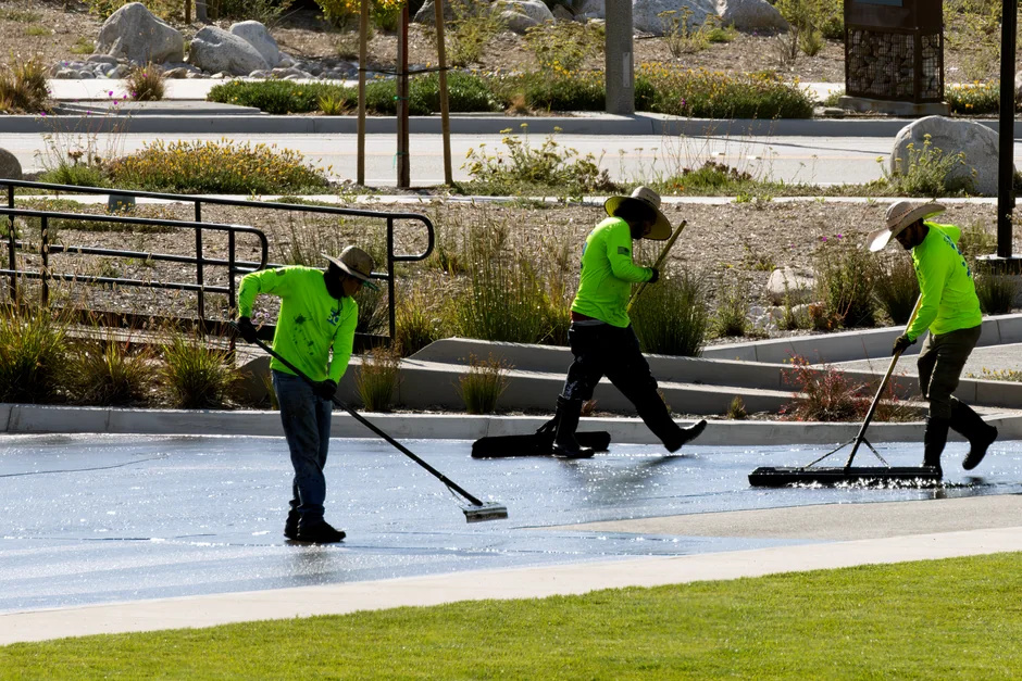 Two workers cleaning windows on a glass building facade using a lift platform, enhancing building aesthetics.